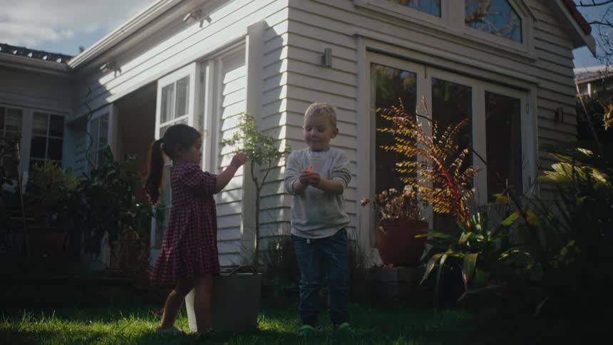 A couple of children playing with plants on a garden in the backyard