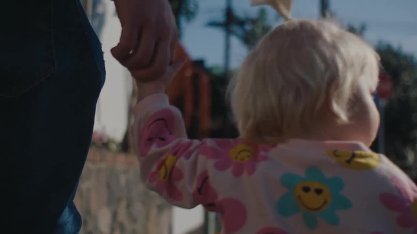 Portraits of a little girl walking down the street holding an adults hand