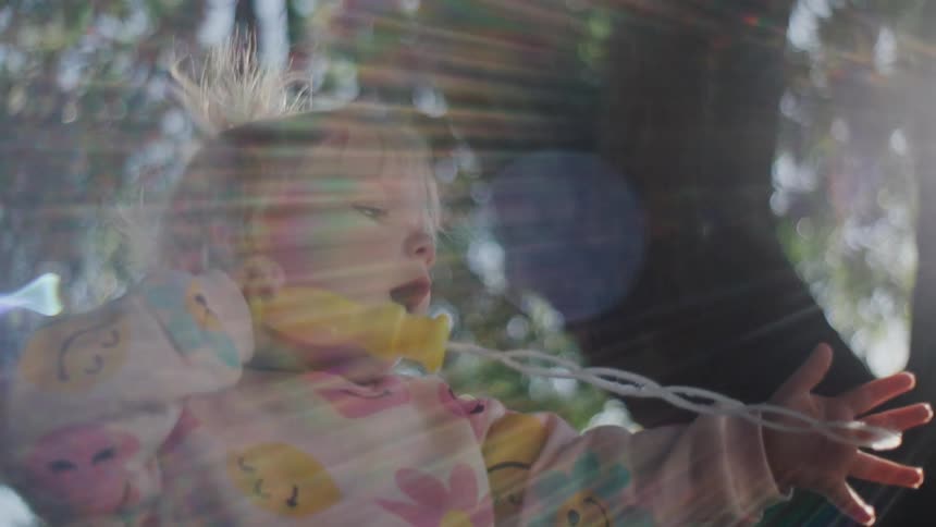 Little girl under a tree holding and playing with a toy