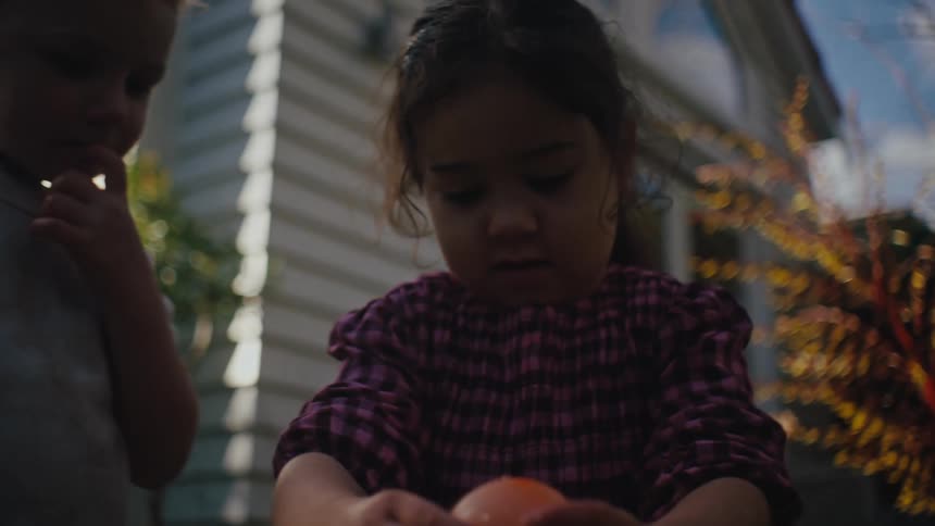 A child is holding a water balloon in the yard