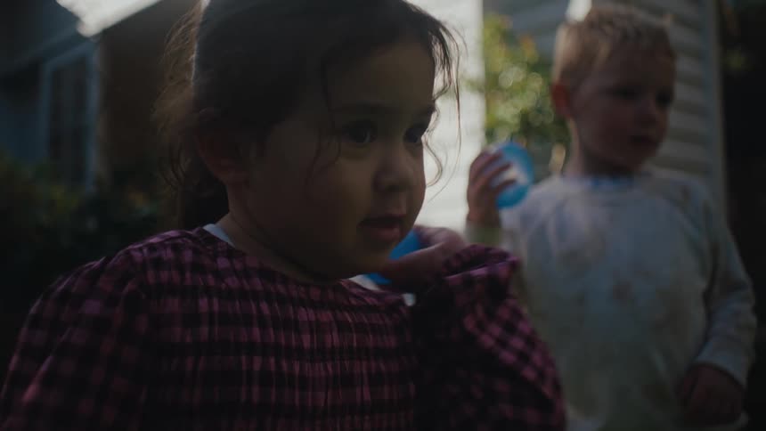 A couple of children play with water balloons in the backyard