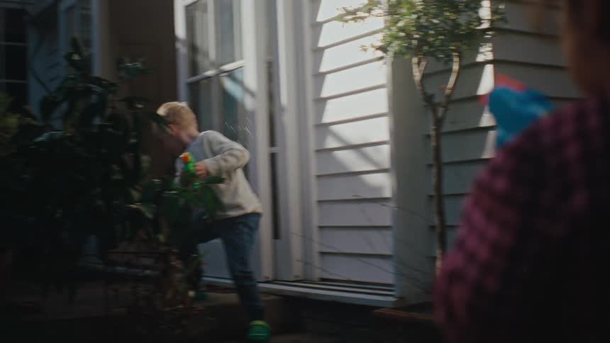 A young boy and girl play with water guns outside on a summer day