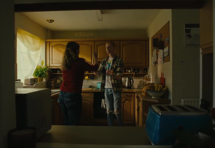 Teenage man and woman in kitchen dancing together