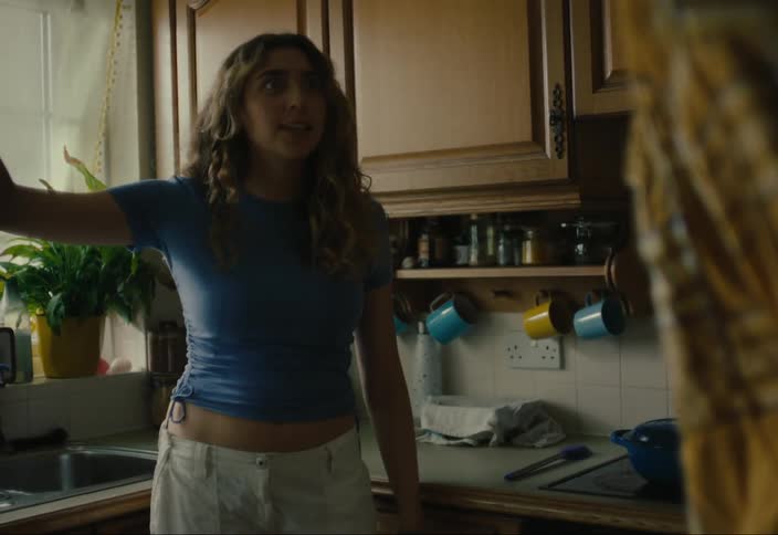 Young blonde woman in the kitchen talking to another person