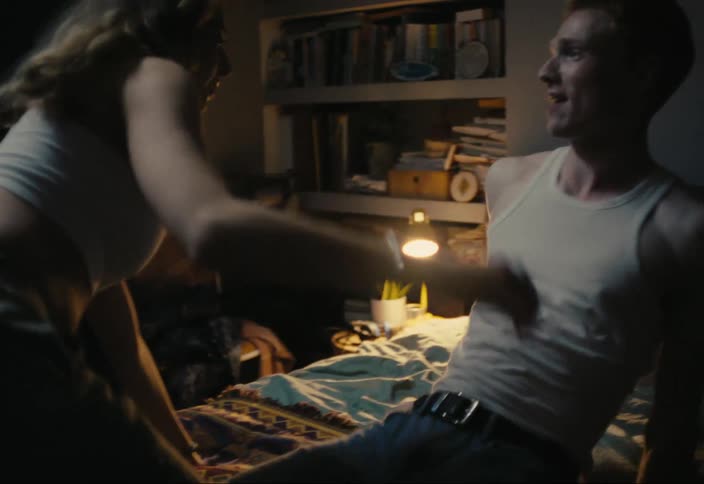 Two teenagers kissing and taking off their tops and lying on the bed