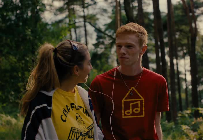 A young couple listening to music sharing earbuds and reclining on each other outdoors
