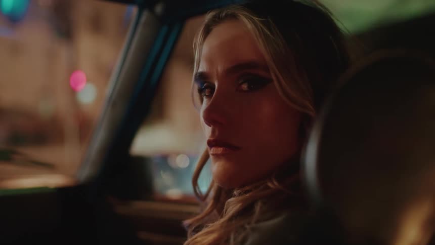 Portrait of a young blonde woman in the front seat of a car looking back