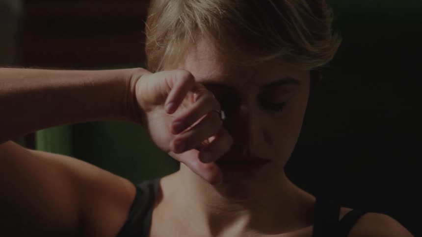 Blonde woman running her hand over her face with a discouraged facial expression