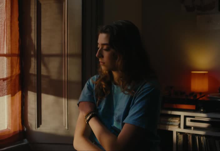 Woman standing in a room in the house looking out the window thoughtfully