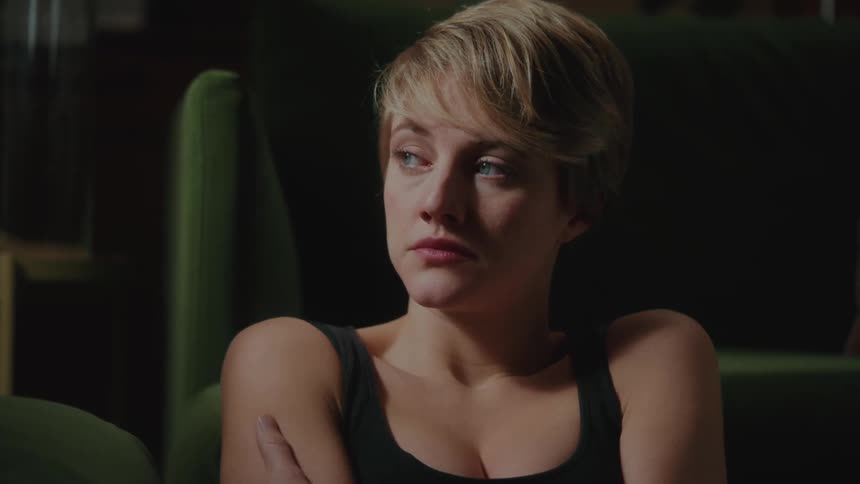 Blonde woman sitting looking to the side with sad facial expression