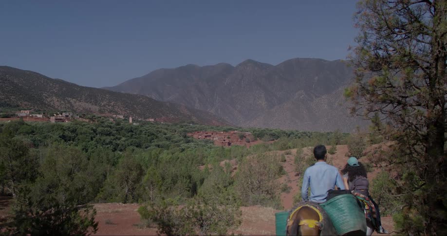 Two people riding horses in a dry region with sparse vegetation