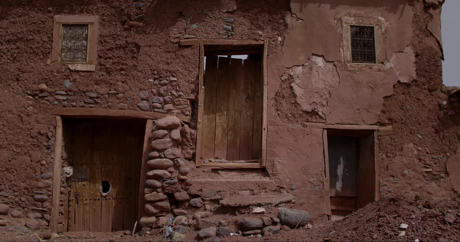 Facade of a precarious clay house with wooden doors and windows