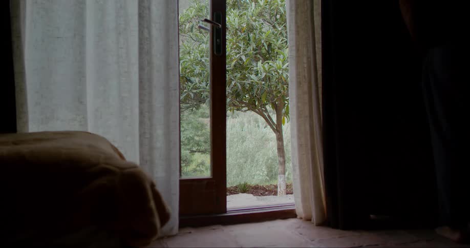 Person closing the curtain of a room in the house