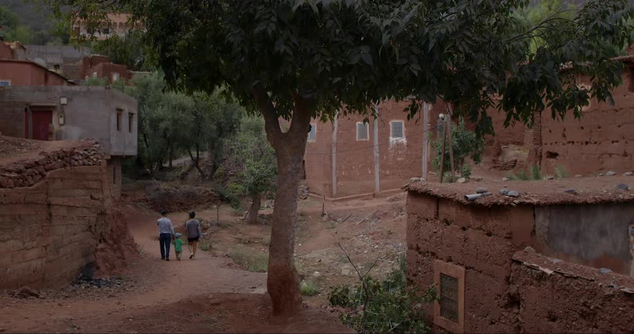 Urban neighborhood with clay houses in a developing country and in the background a family walking