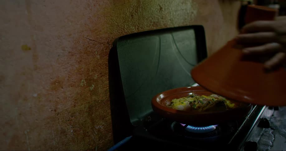 Close up of a womans hands holding a cutlery and cooking in a clay pot on the stove