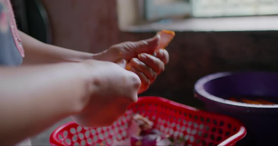 A woman uses a knife to carve carrots in a kitchen