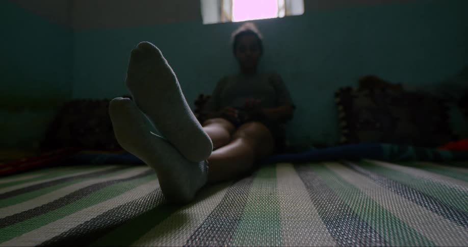 A woman sits against a wall and stretches her legs out across the carpet