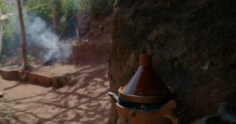 Clay pot stands near a wall while smoke rises in the background
