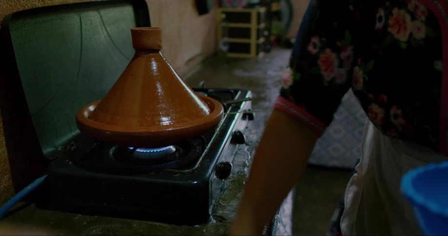 Woman wiping the sink while cooking with a clay pot on the stove