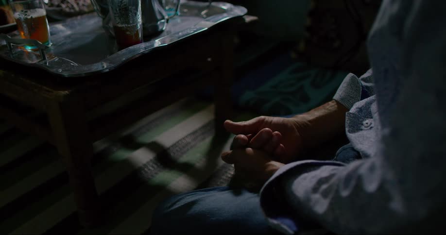 Close up of hands of a person sitting in front of a table with cup of tea
