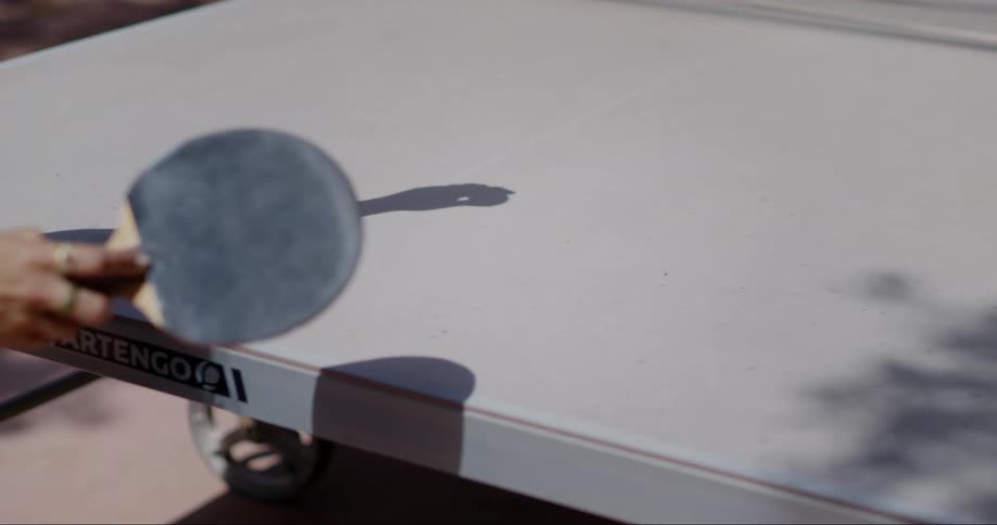A person playing table tennis with a focus on the players arm and paddle as they hit the ball