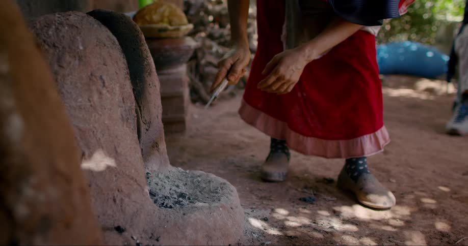 Womans hand with a stick preparing a homemade clay oven