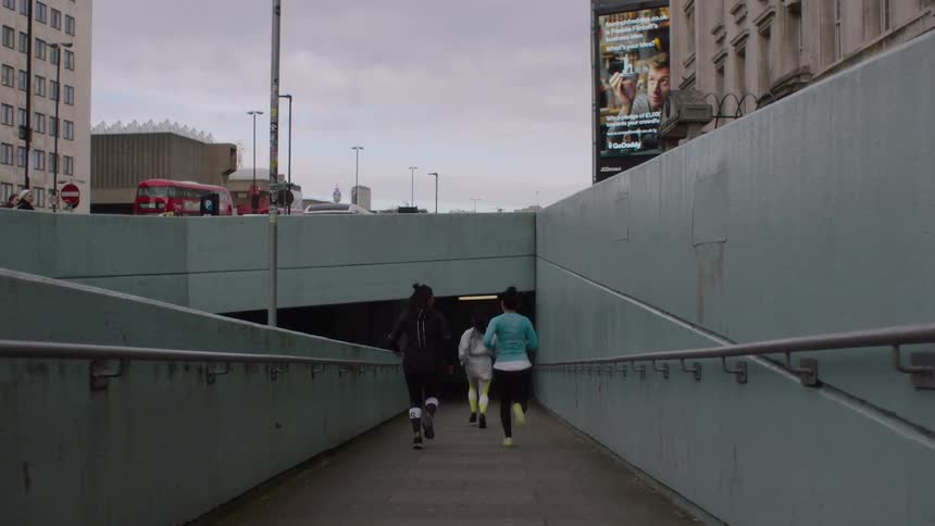 Group of three women running into an overpass