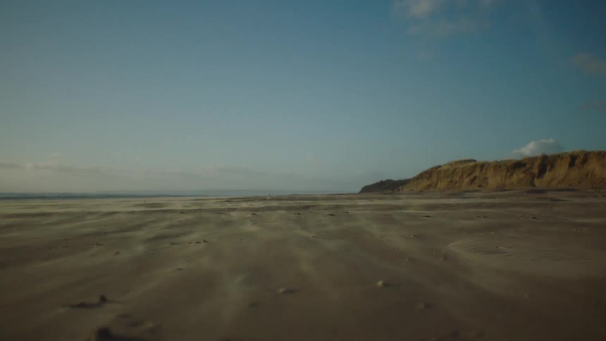 A vast sandy beach stretching towards a distant horizon under a clear blue sky