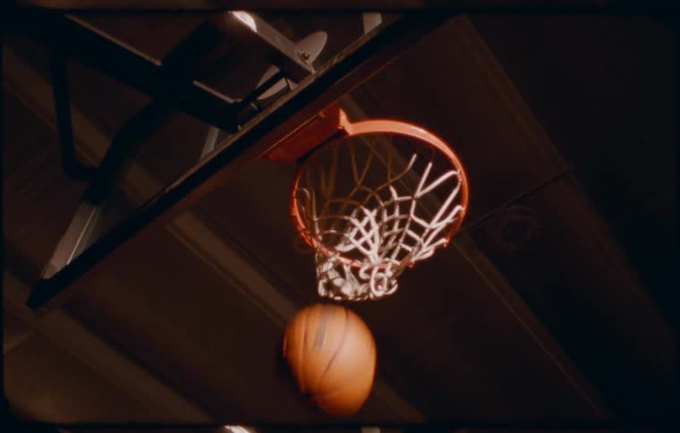A basketball hoop with a white net hanging from a metal rim against a dark background