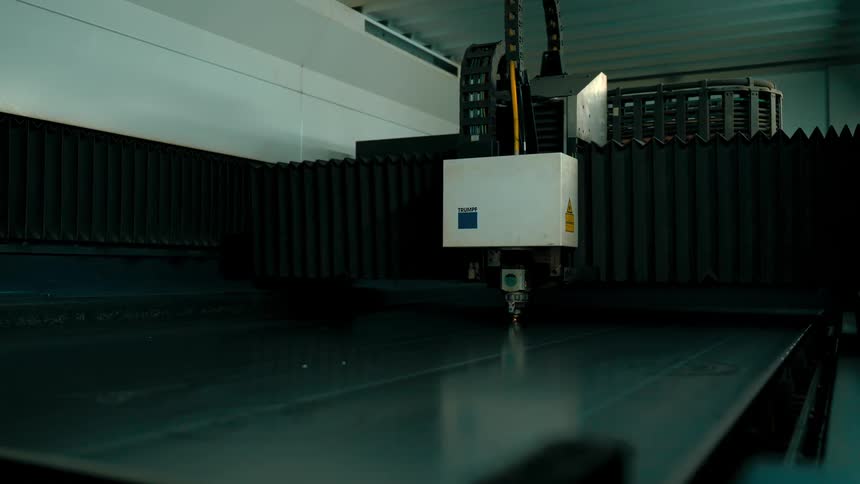 Machine creates sparks while working on a large metal sheet in a factory