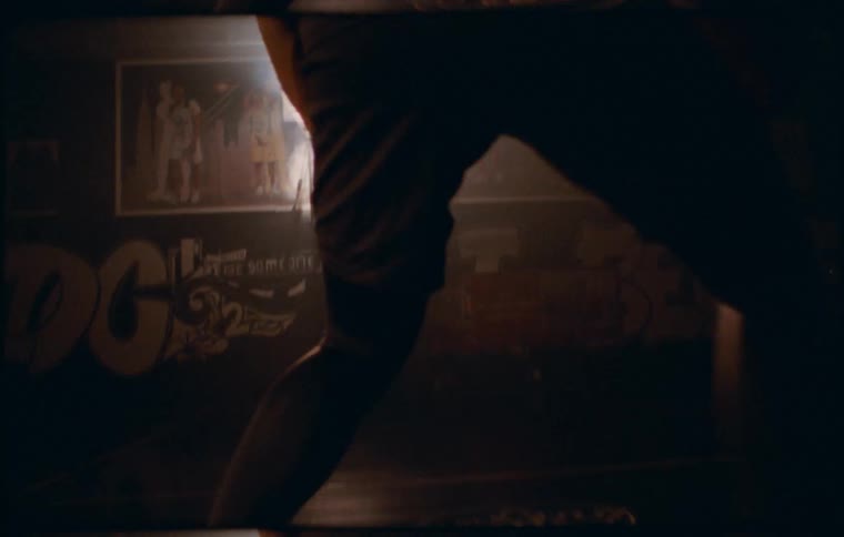 A black man runs and dribbles a basketball on a dark court