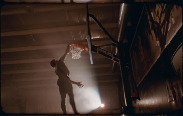 A young man performing a slam dunk in an indoor basketball court