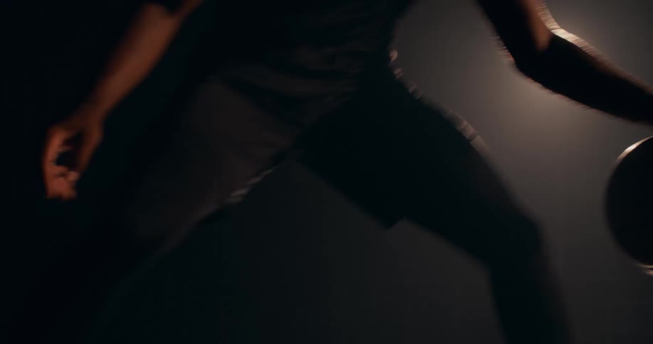Close up of a young man dribbling a basketball on a dimly lit court