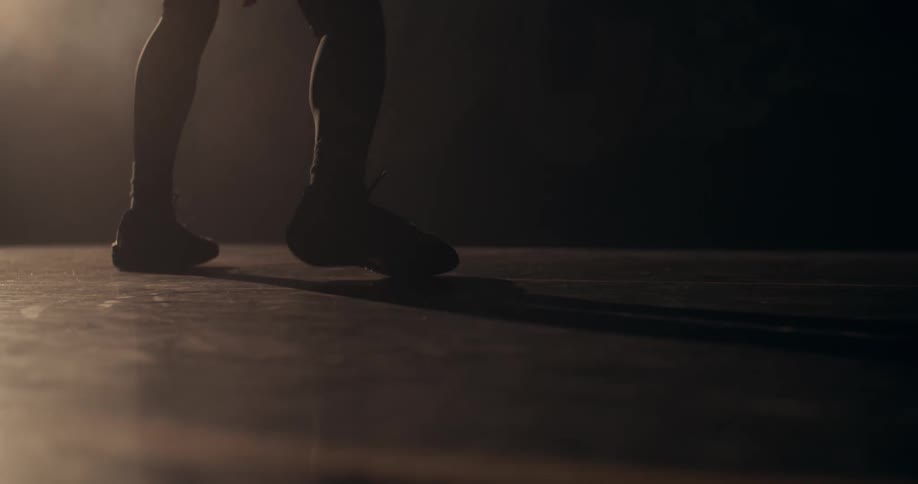 A closeup of a person dribbling a basketball on a court
