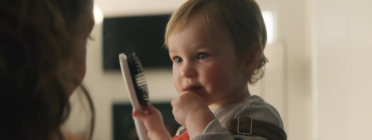 Little girl eating and combing her mothers hair