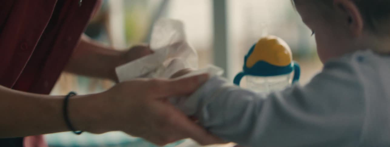 A mother cleans her daughters hands and mouth with a piece of cloth