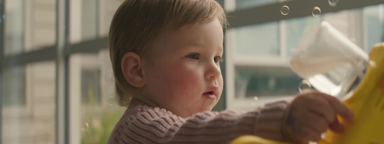 Little girl holding a toy that blows soap bubbles