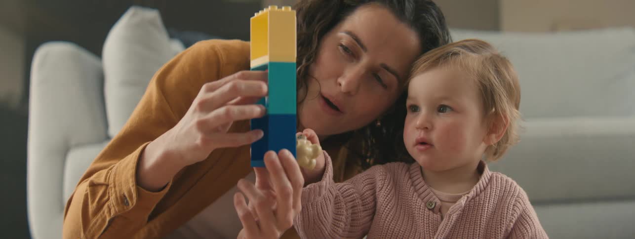 Woman and a child joyfully playing together building structures with colorful blocks on a bright cheerful surface