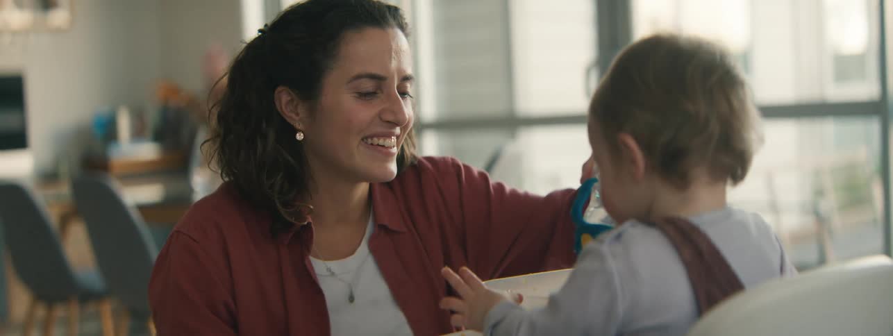 Cheerful mother interacting with her little daughter who is sitting