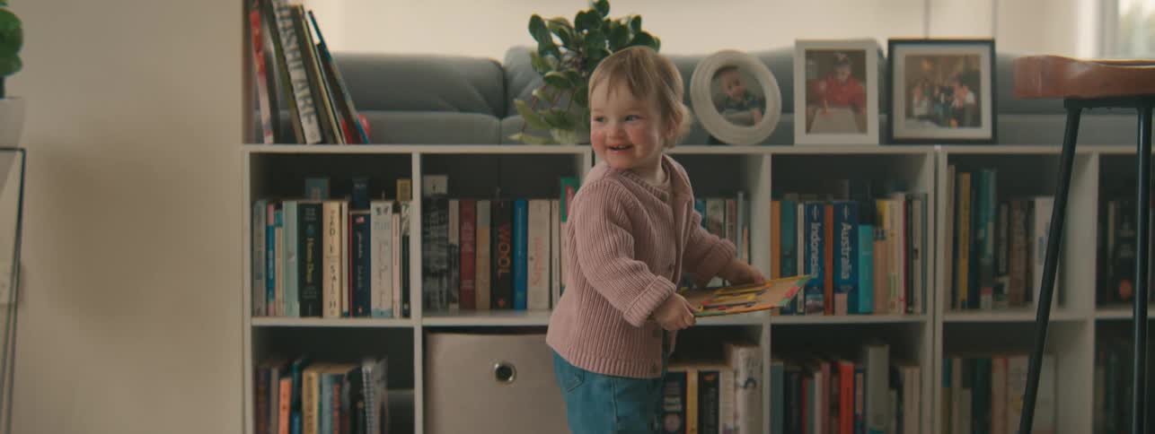 Little girl picking up a book and her mother holding her in her arms playing