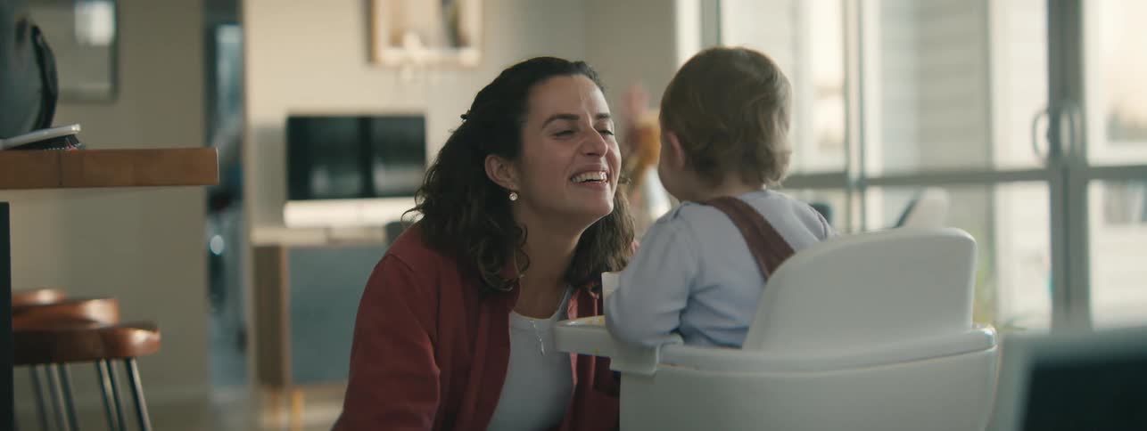 Mother playing with her little daughter who is sitting eating