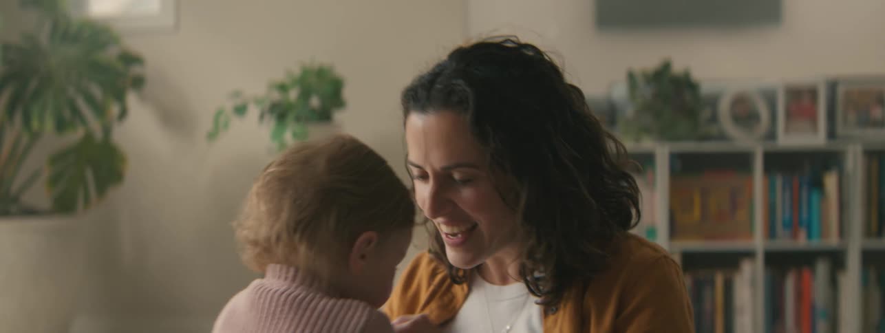Mother smiles while playing with her baby