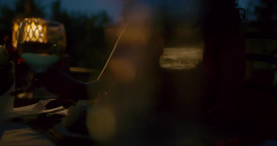 Woman sitting at a table at night drinking a glass of wine