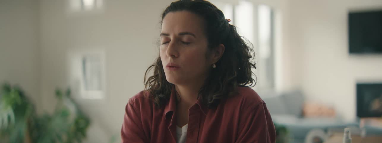 Relaxed young woman reflecting and practicing self-care in soft light.