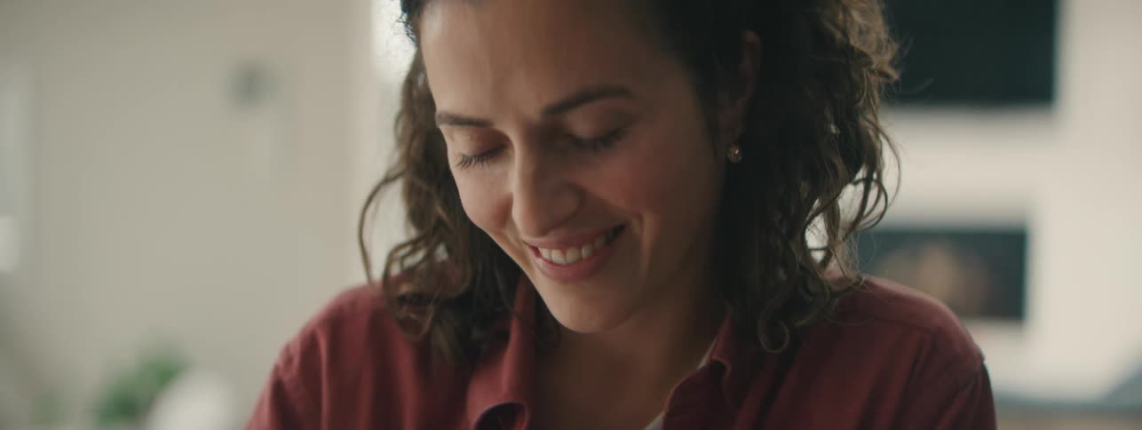 Gentle woman looking down with a thoughtful, natural smile.