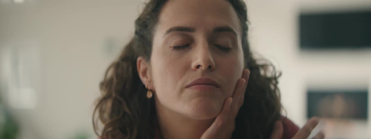 Woman resting head on hand with eyes closed indoors.
