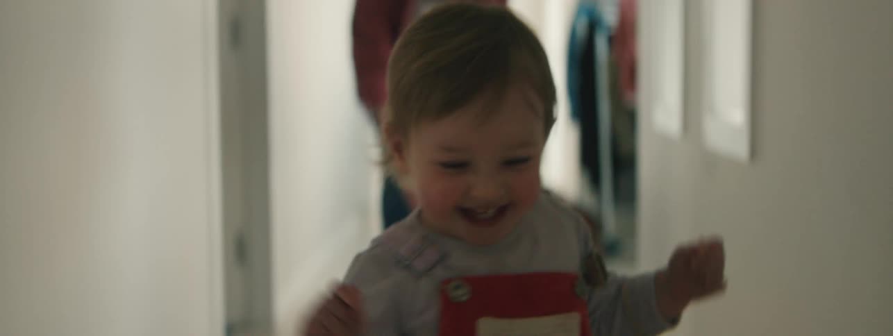 A child runs away from her mother who is playfully chasing her in a hallway