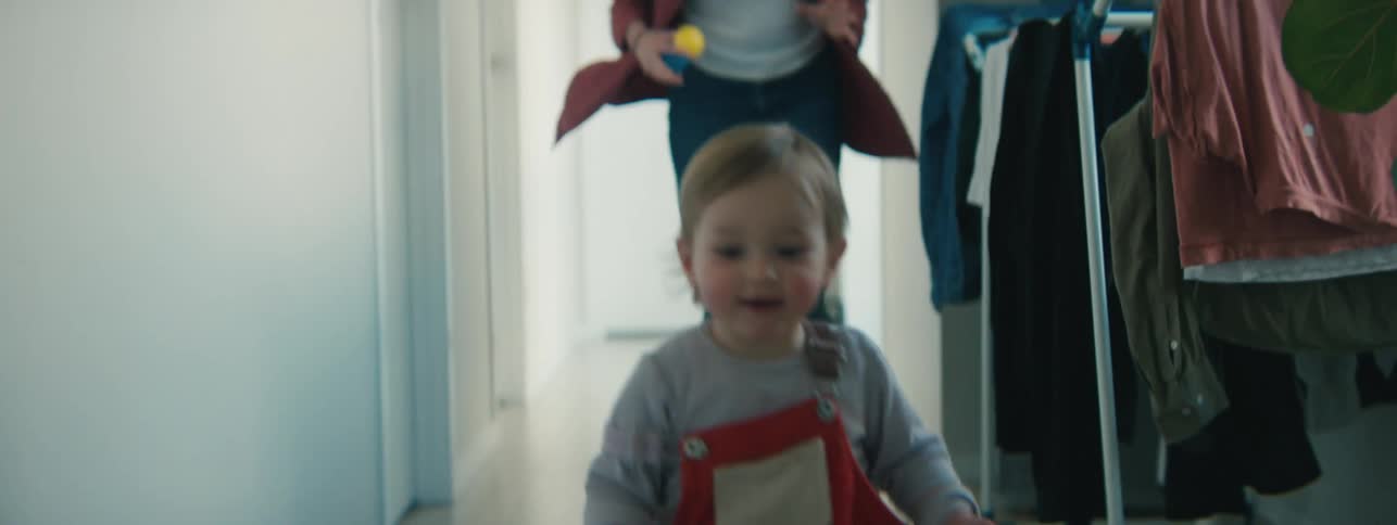 Mother running after her little daughter in the hallway playing and holding her in her arms