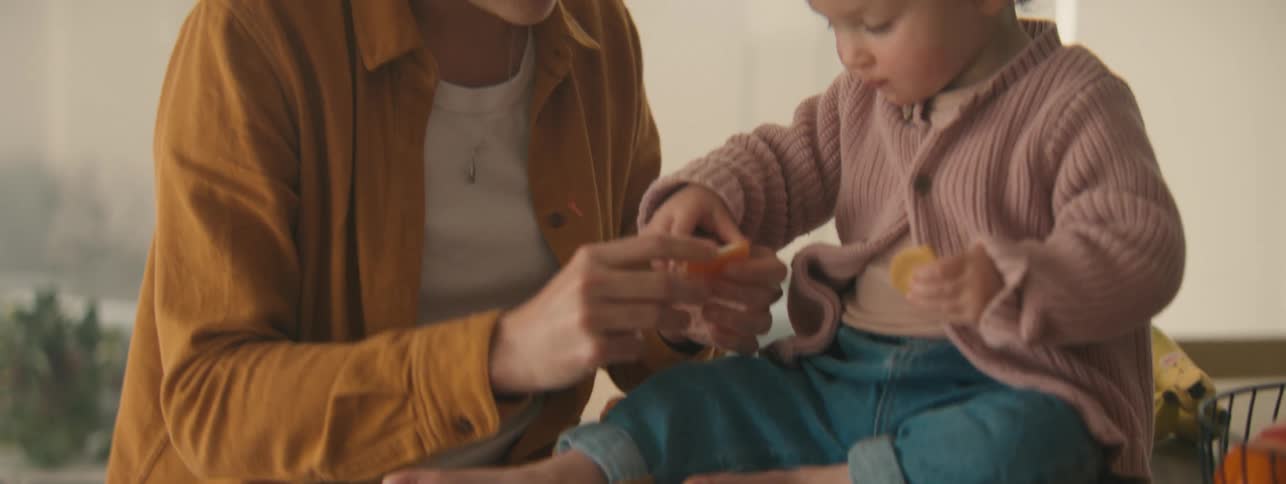 A clip of a mother pealing an orange for a kid