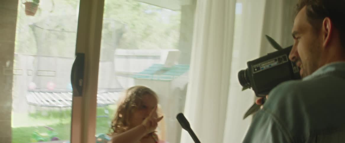 A father filming and interviewing his two smiling and joyful children